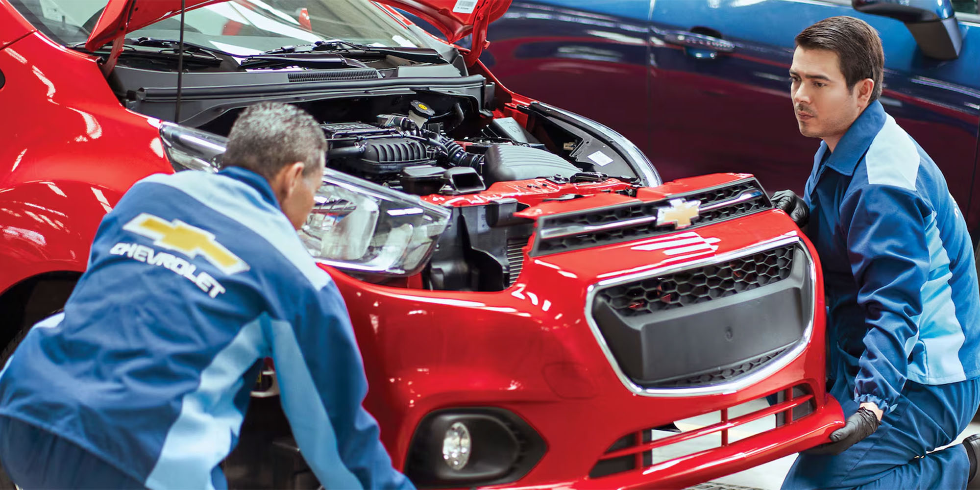 Dos técnicos Chevrolet trabajando en un auto